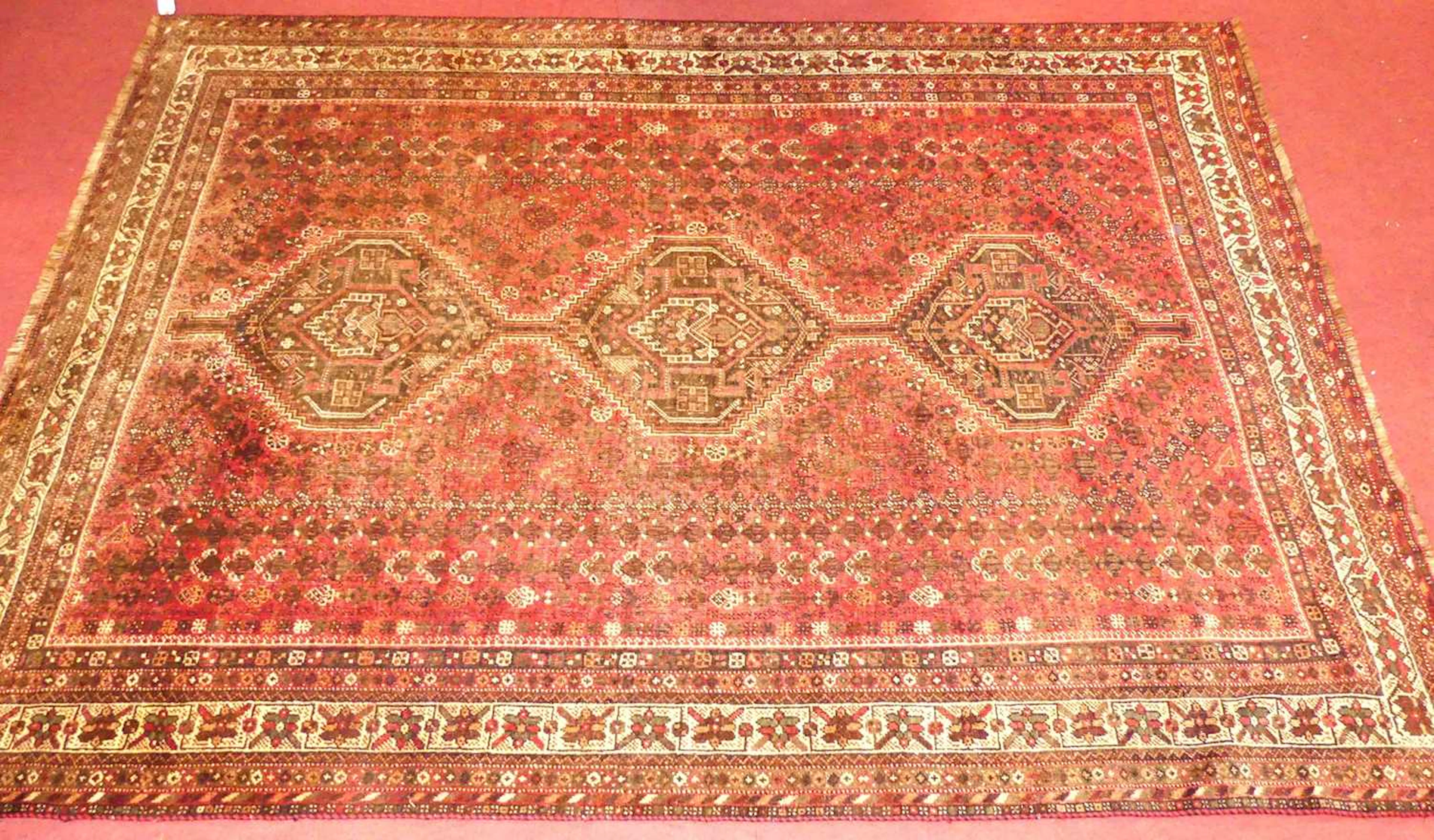 Lot 773 - A Persian woollen red ground Shiraz rug, 300