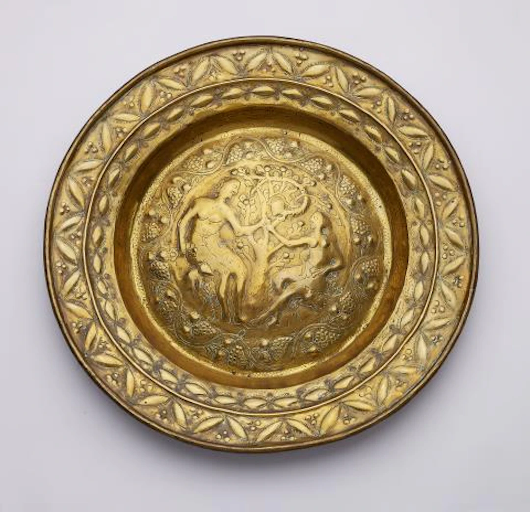 A brass alms bowl with Adam and Eve