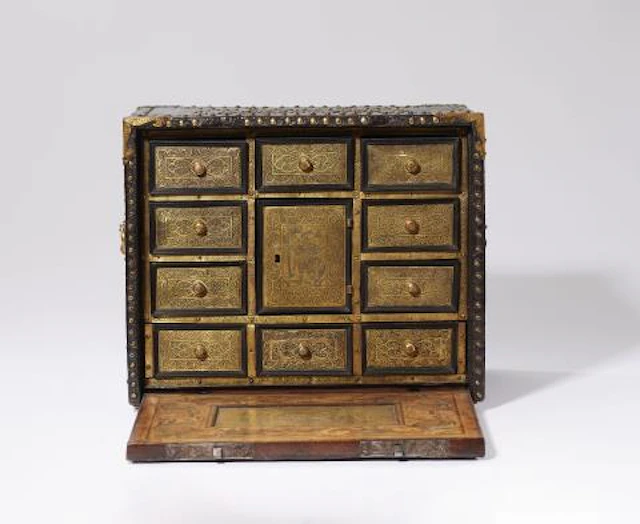 A cabinet with marquetry and riveted leather covering