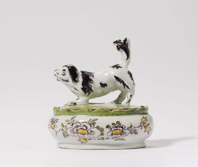 A Dutch Delft faience butter dish with a barking Spaniel