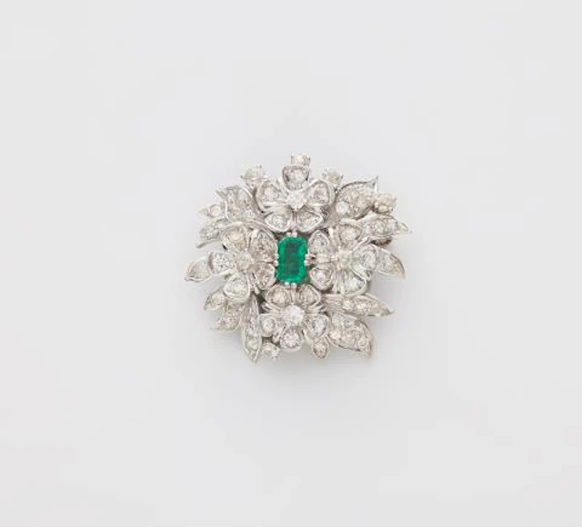 An 18k white gold diamond and emerald brooch made from a former clasp.