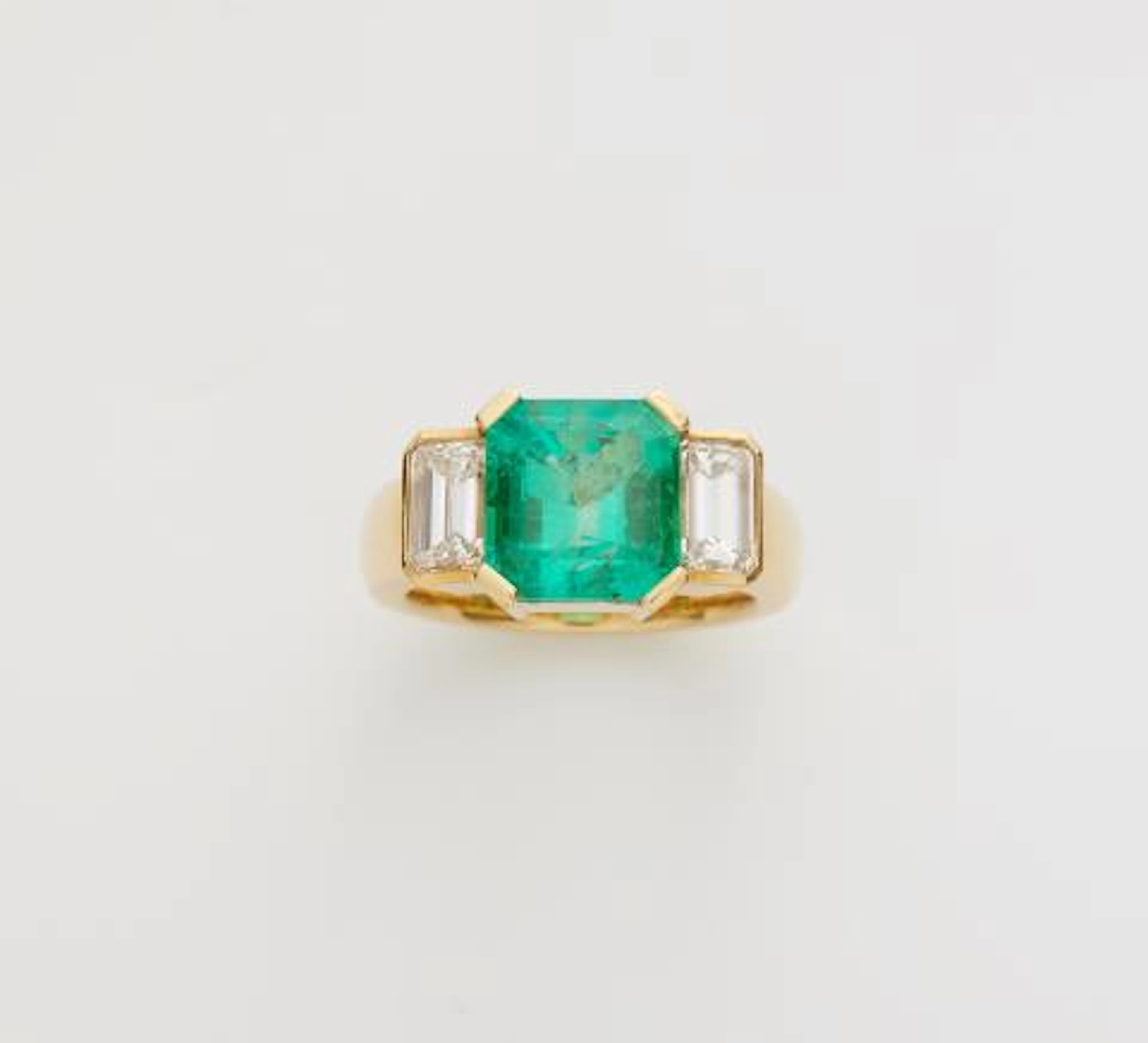 An 18k yellow gold diamond and Colombian emerald three stone ring.