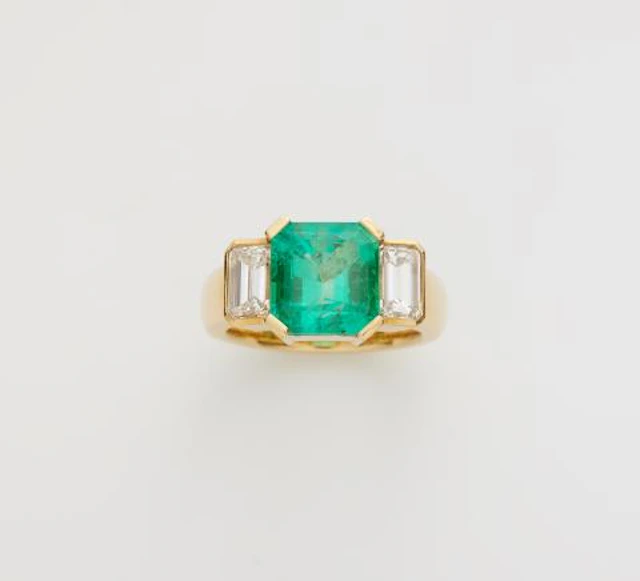 An 18k yellow gold diamond and Colombian emerald three stone ring.