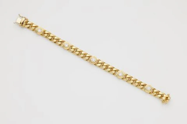 An 18k yellow gold curb chain bracelet with brilliant-cut diamonds.