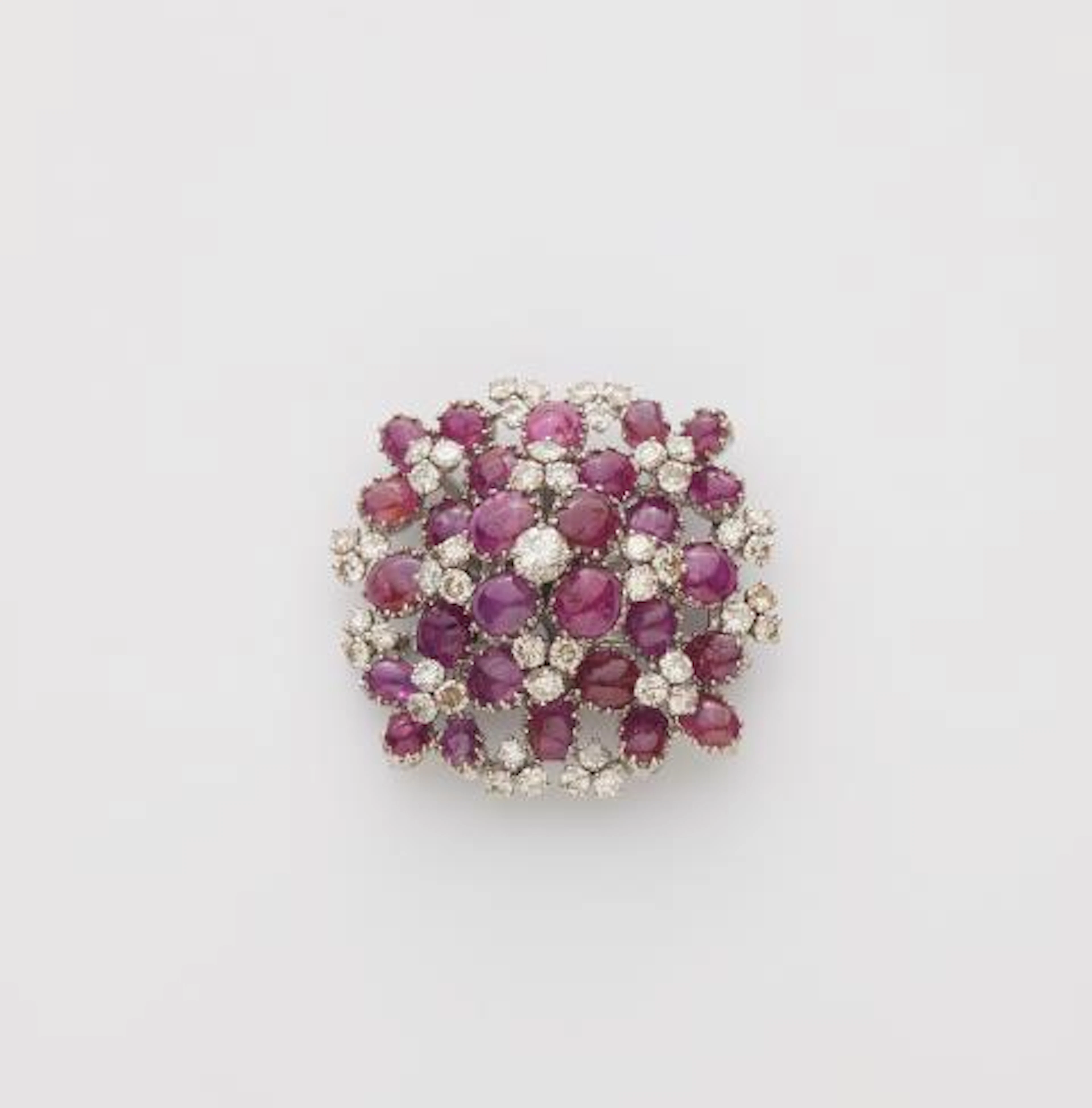 An 18k white gold diamond and ruby cabochon cocktail brooch.