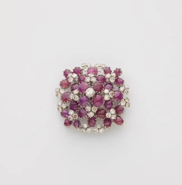 An 18k white gold diamond and ruby cabochon cocktail brooch.