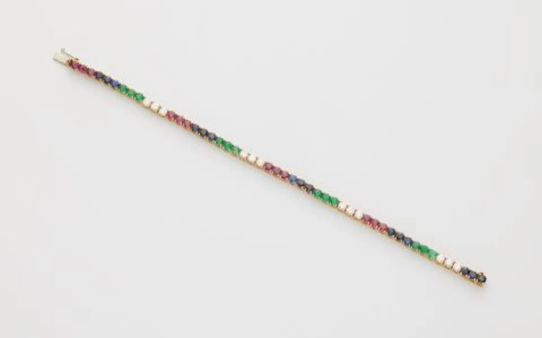 An Italian 18k white gold ruby sapphire emerald and diamond rivière bracelet.
