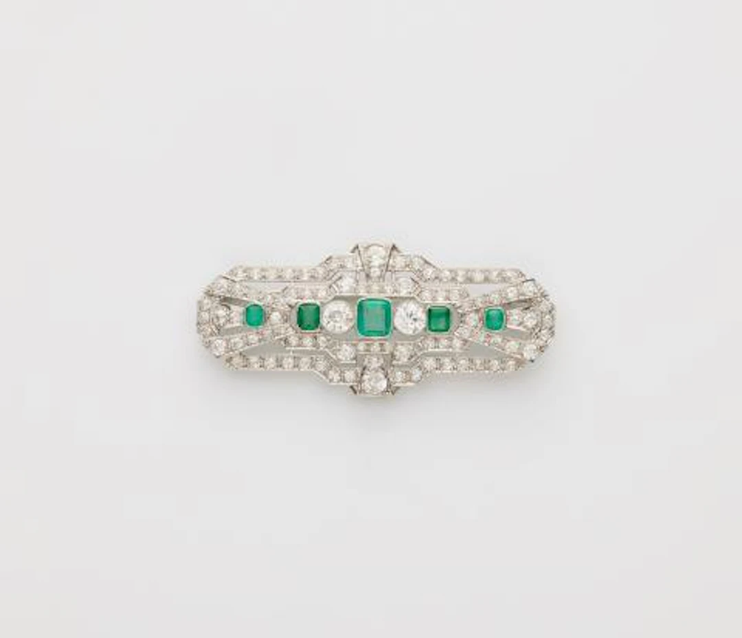 A 14k white gold diamond and emerald Art Déco brooch.