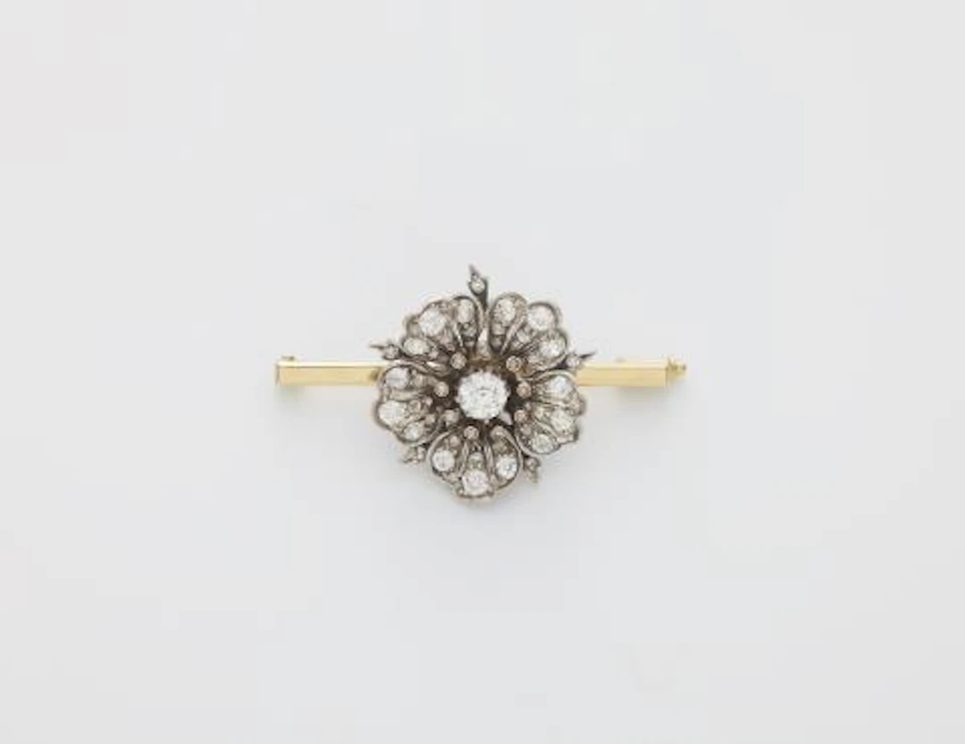 A 14k white gold and diamond wild rose blossom later mounted on a bar brooch.