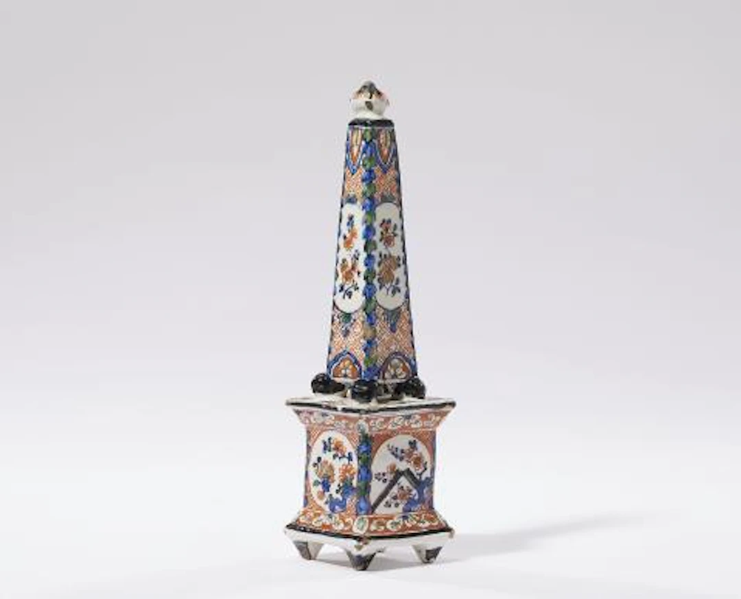A Dutch Delft faience table obelisk with flowers in reserves