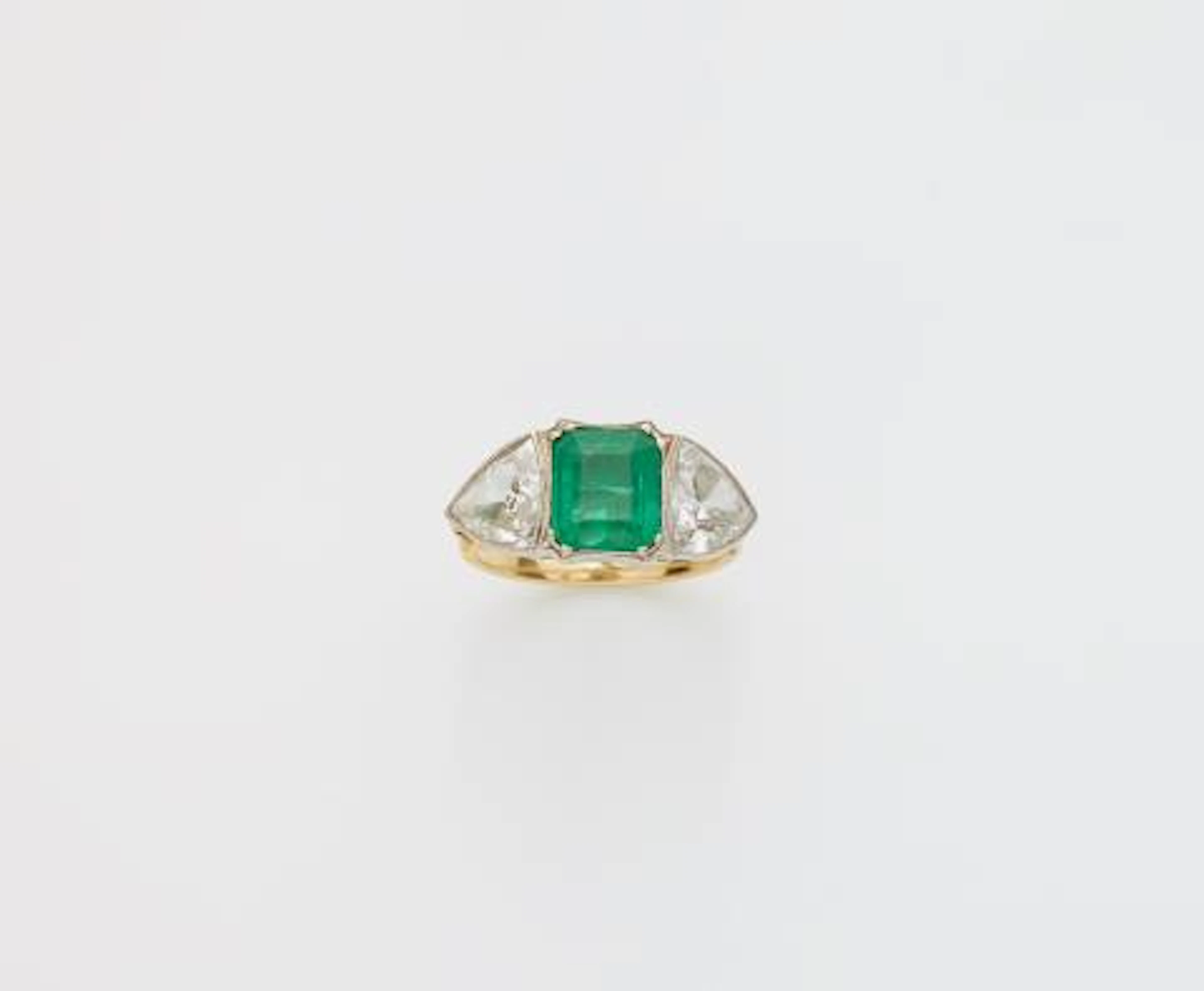 An 18k gold emerald and triangle-cut diamond three stone ring.