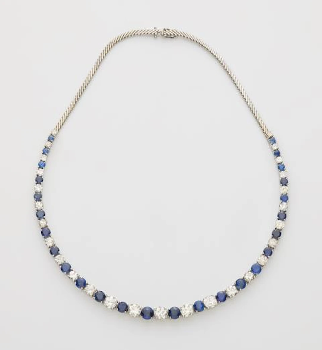 A flexible 18k white gold sapphire and diamond rivière necklace.