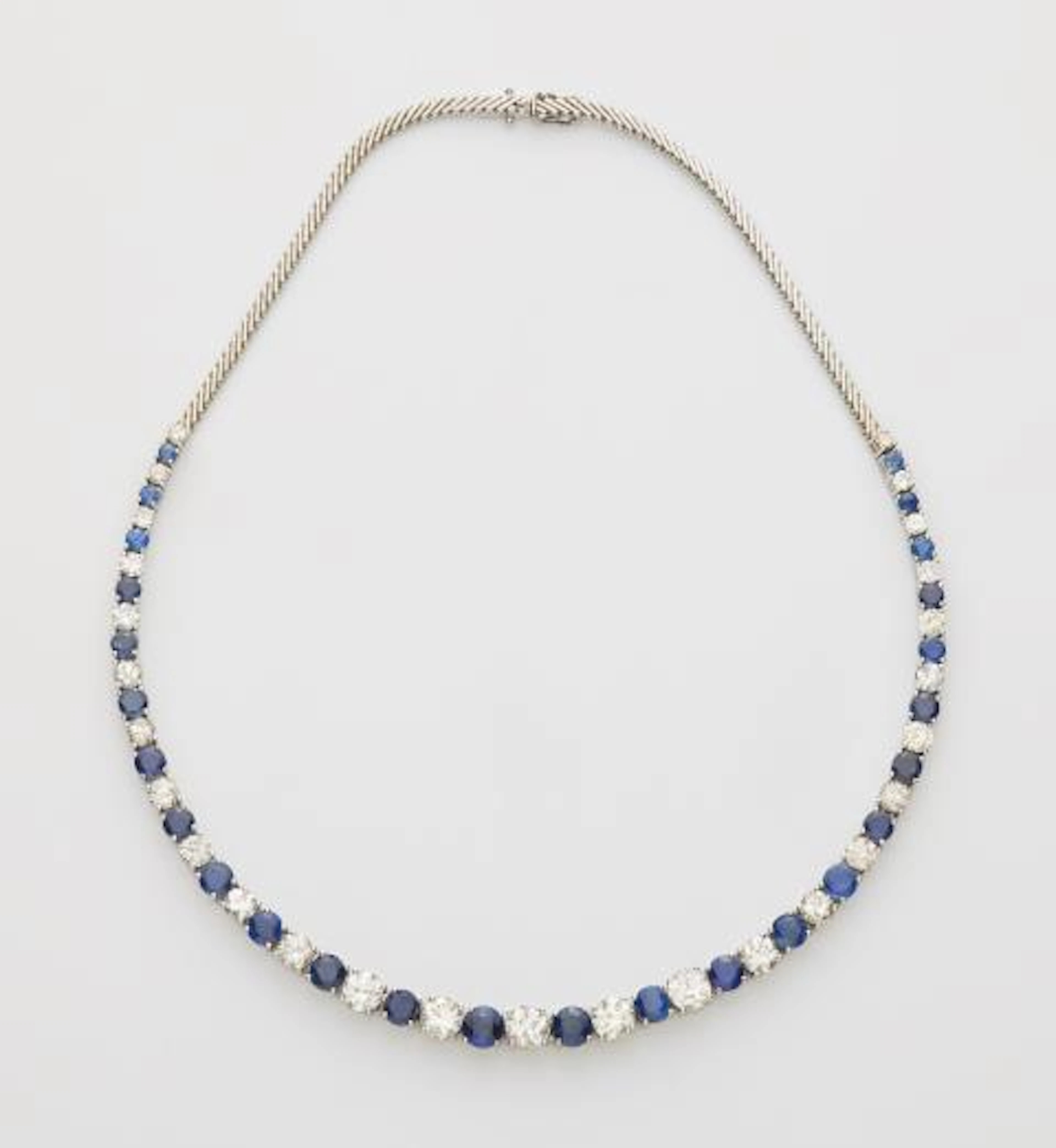 A flexible 18k white gold sapphire and diamond rivière necklace.