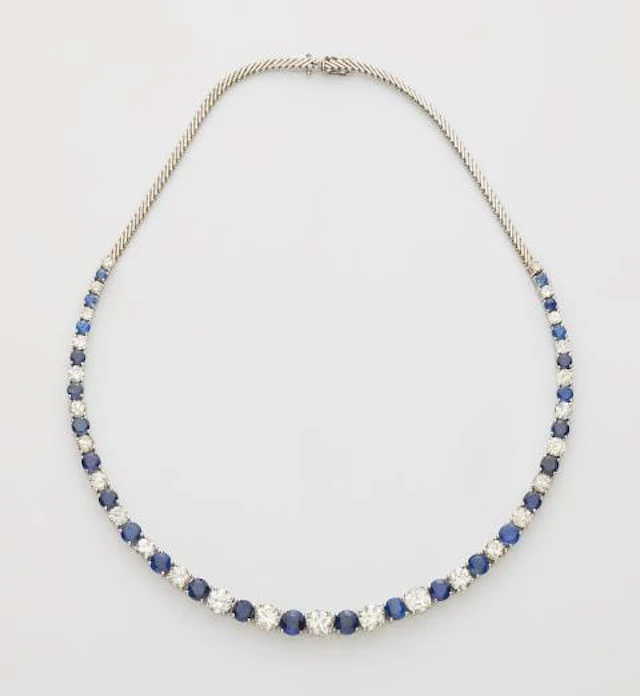 A flexible 18k white gold sapphire and diamond rivière necklace.