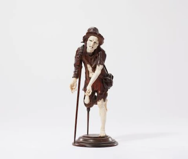 A carved ivory and fruitwood figure of a beggar