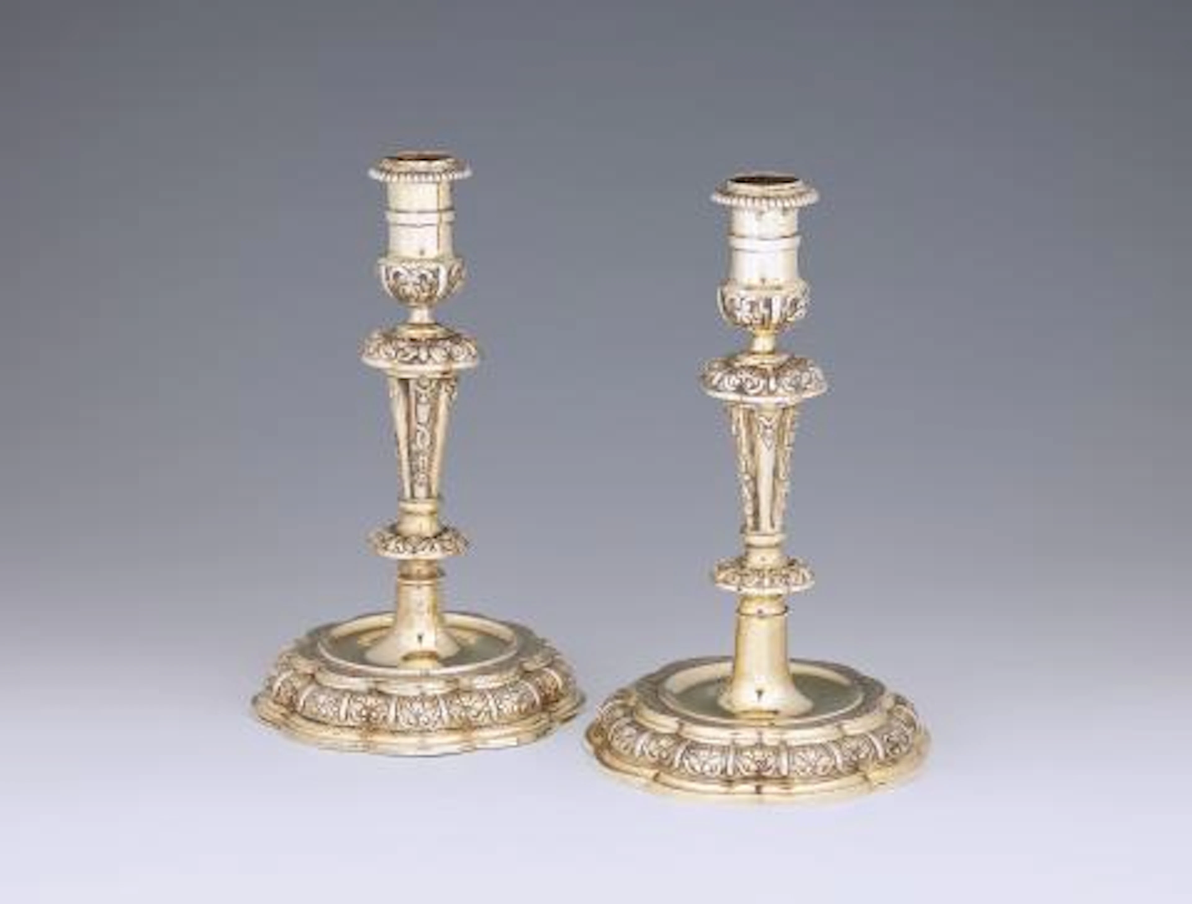 An ornate pair of Regencé silver-gilt candlesticks