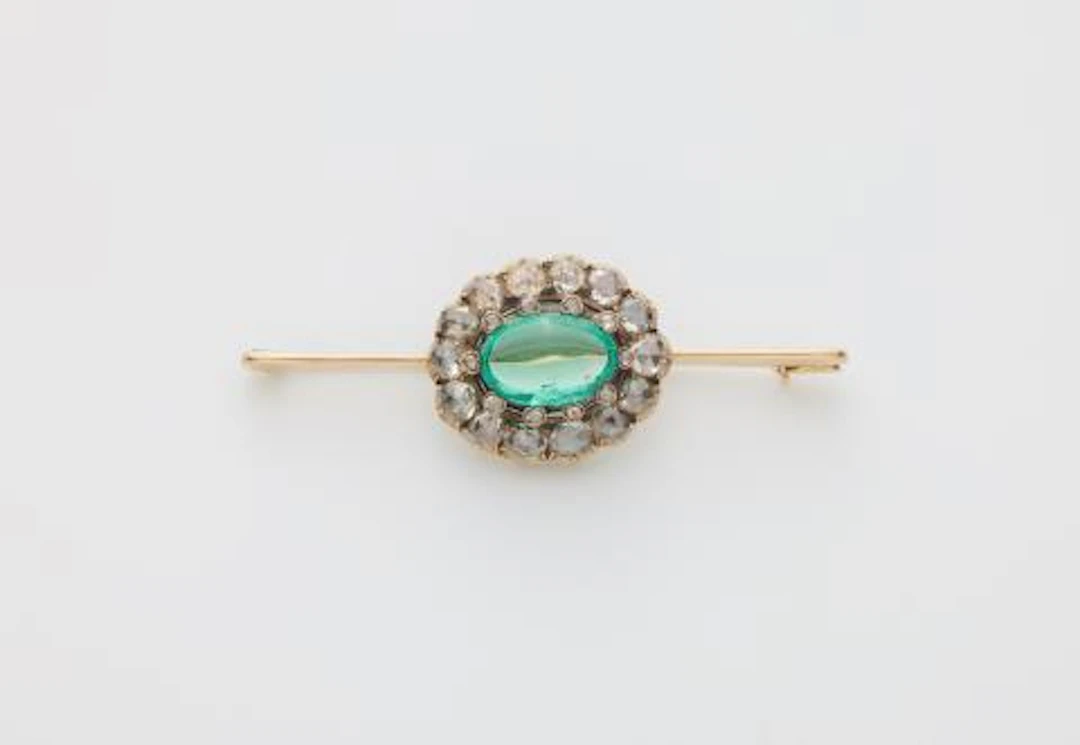 A 14k gold bar brooch with a 19th century rose-cut diamond and emerald