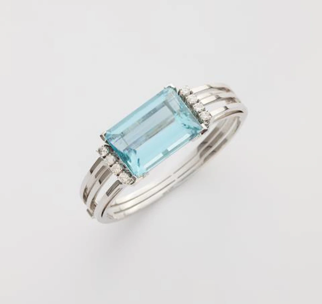 An 18k white gold diamond and large step-cut aquamarine bangle.