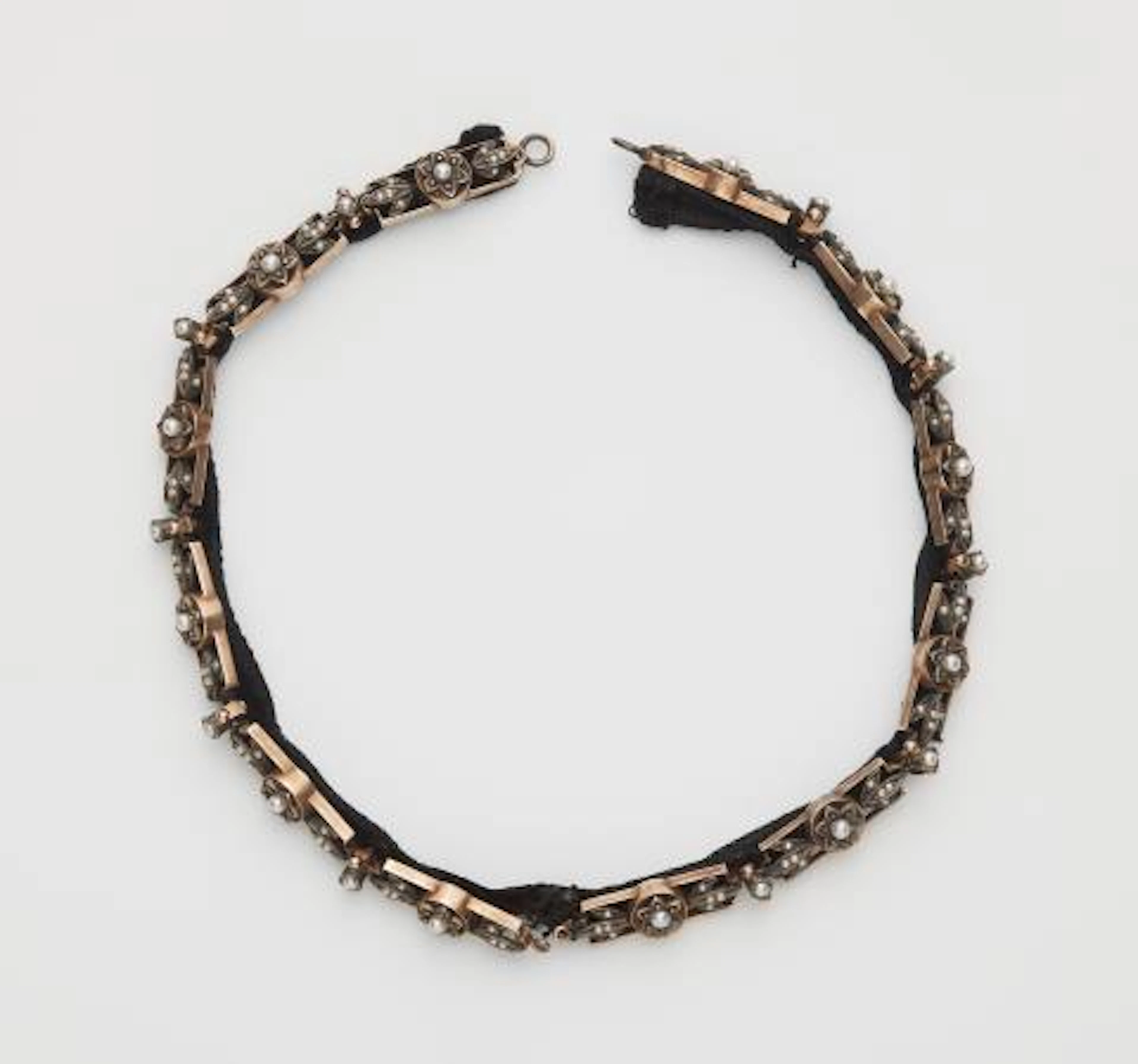A velvet band with sewn on gilded silver and pearl relief decoration.