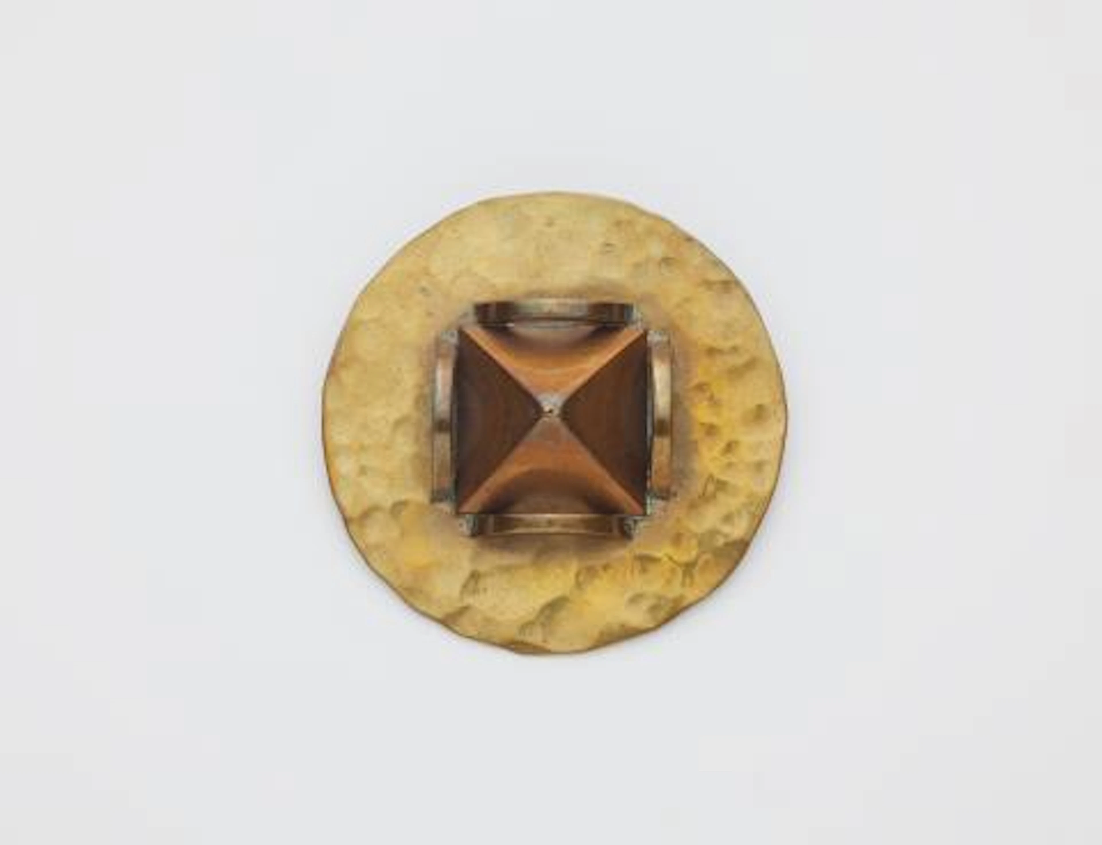 A French hammered brass and copper disc brooch with pyramidal motif.