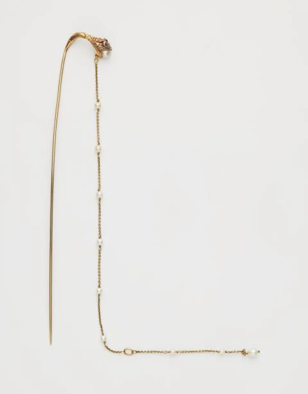 An Art Nouveau 15k yellow gold ruby and baroque pearl hat pin.