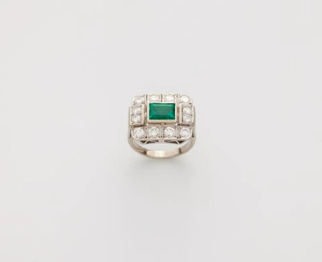 An 18k white gold diamond and fine emerald ring.
