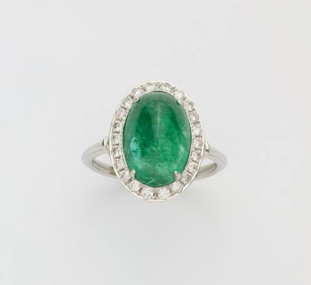 An 18k white gold diamond and sugarloaf-cut emerald cluster ring.