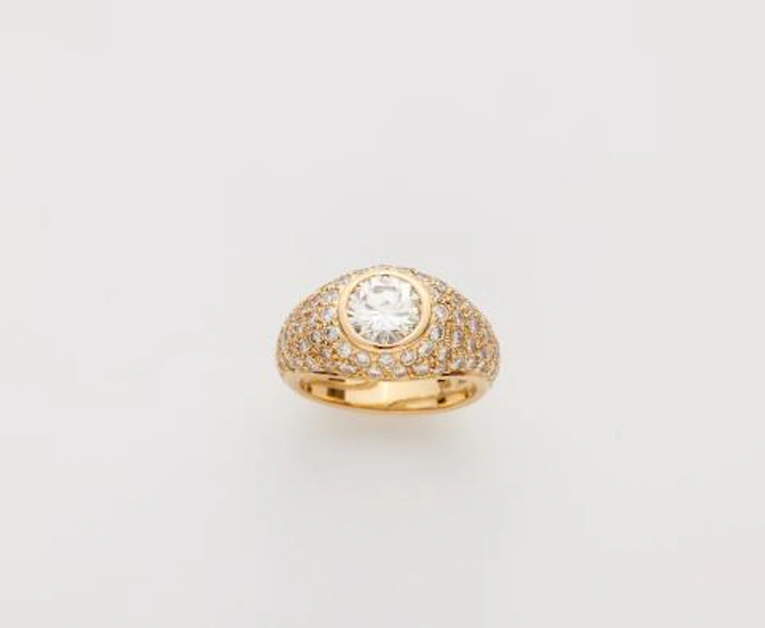 An 18k gold diamond pavé eternity ring with a brilliant-cut diamond solitaire.