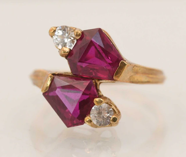 A 10k yellow gold ruby and white stone crossover ring