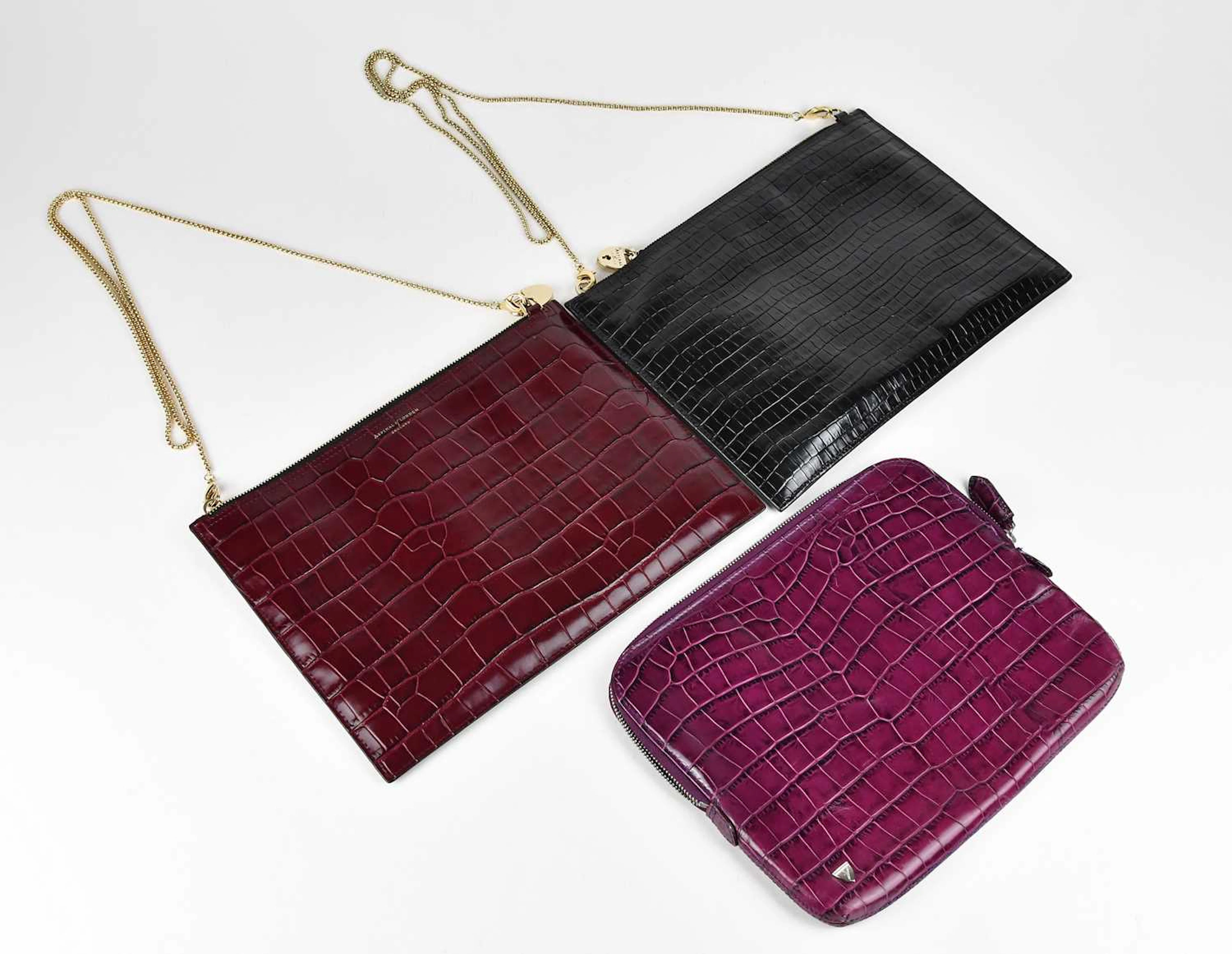 ASPINAL; a black and deep red embossed crocodile clutch bag