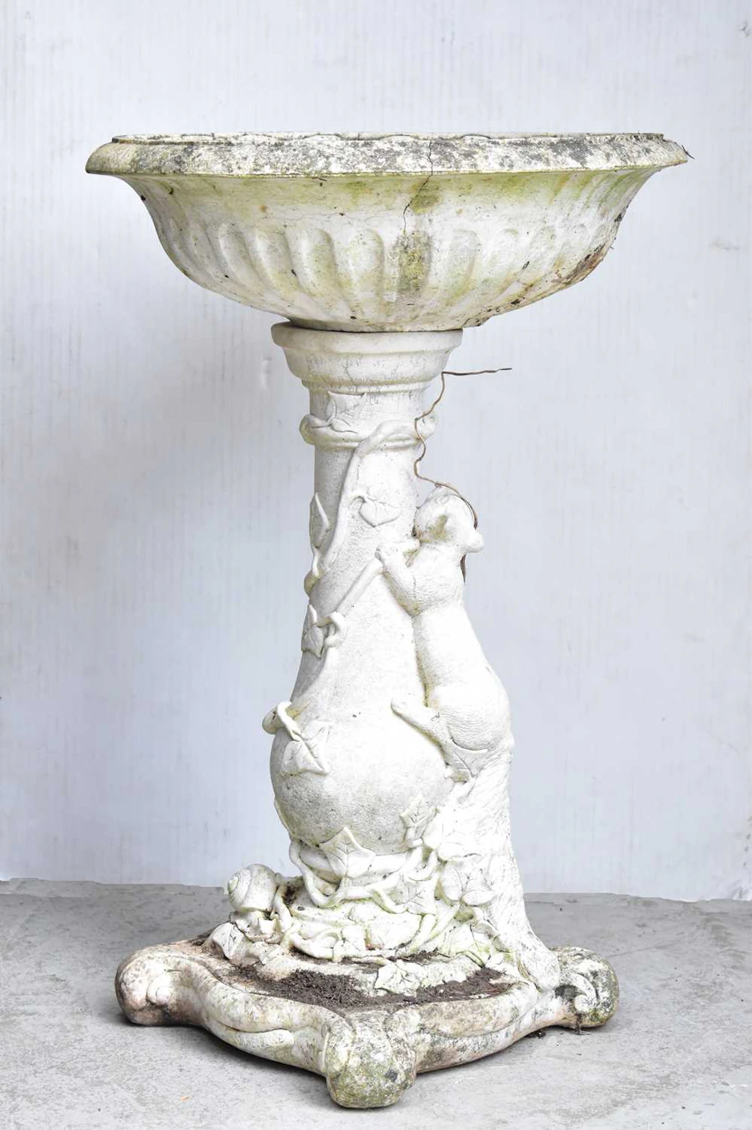 A reconstituted garden birdbath with classical style bowl