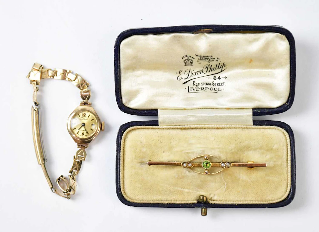 A 9ct yellow bar brooch set with a central peridot and seed pearls