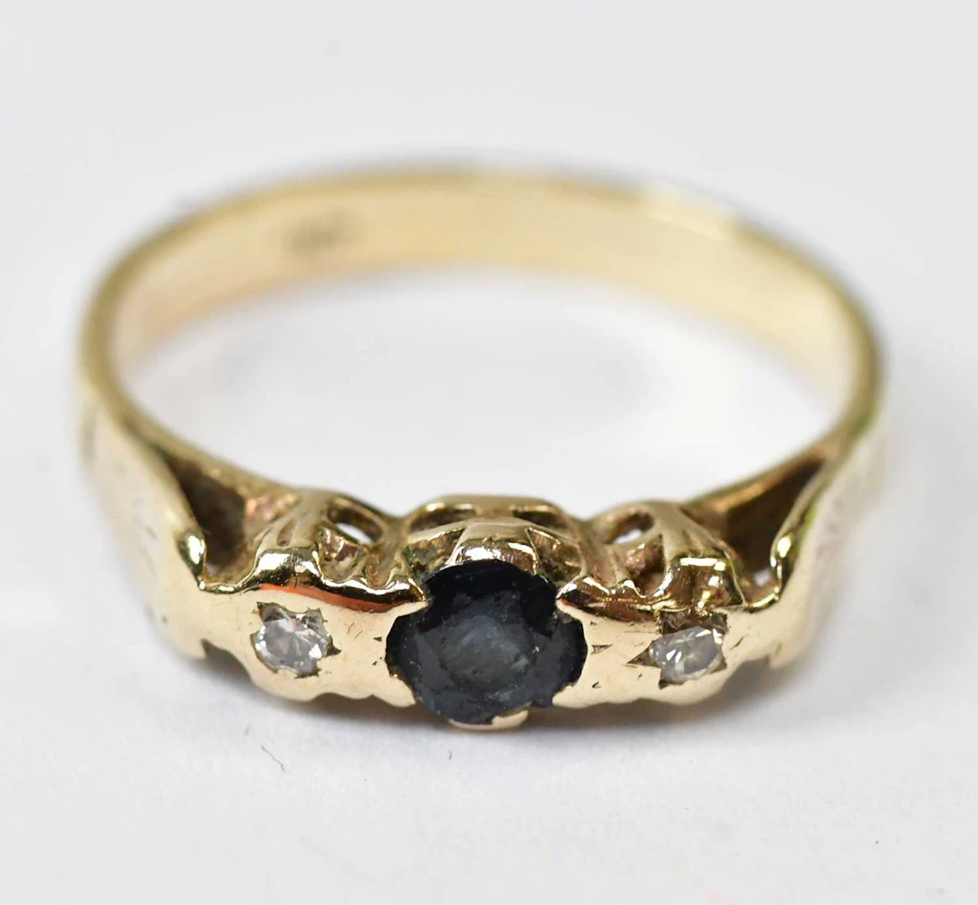 A 9ct yellow gold ring set with a central sapphire and two diamonds