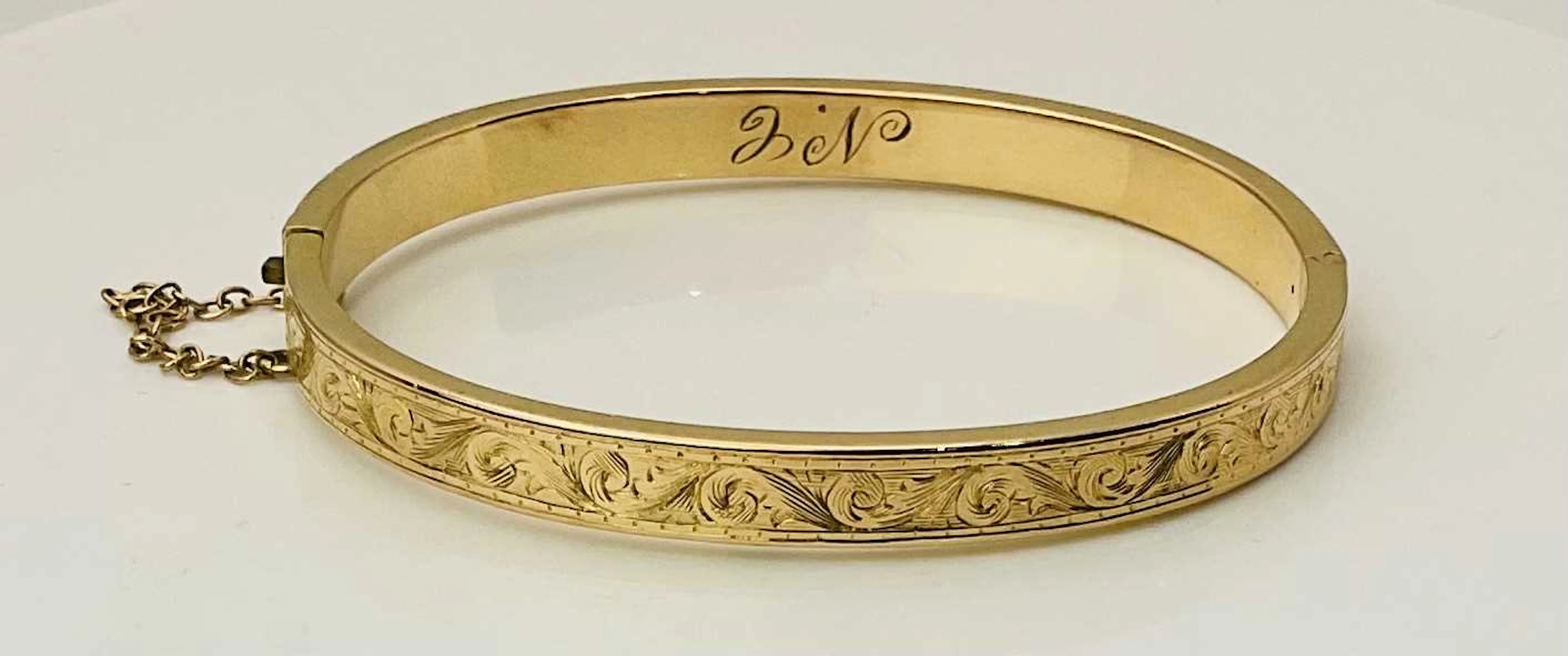 A yellow metal hinged snap bangle with bright cut floral decoration