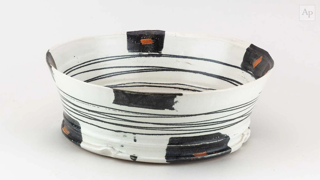 A large stoneware bowl covered in pale grey glaze with iron decoration