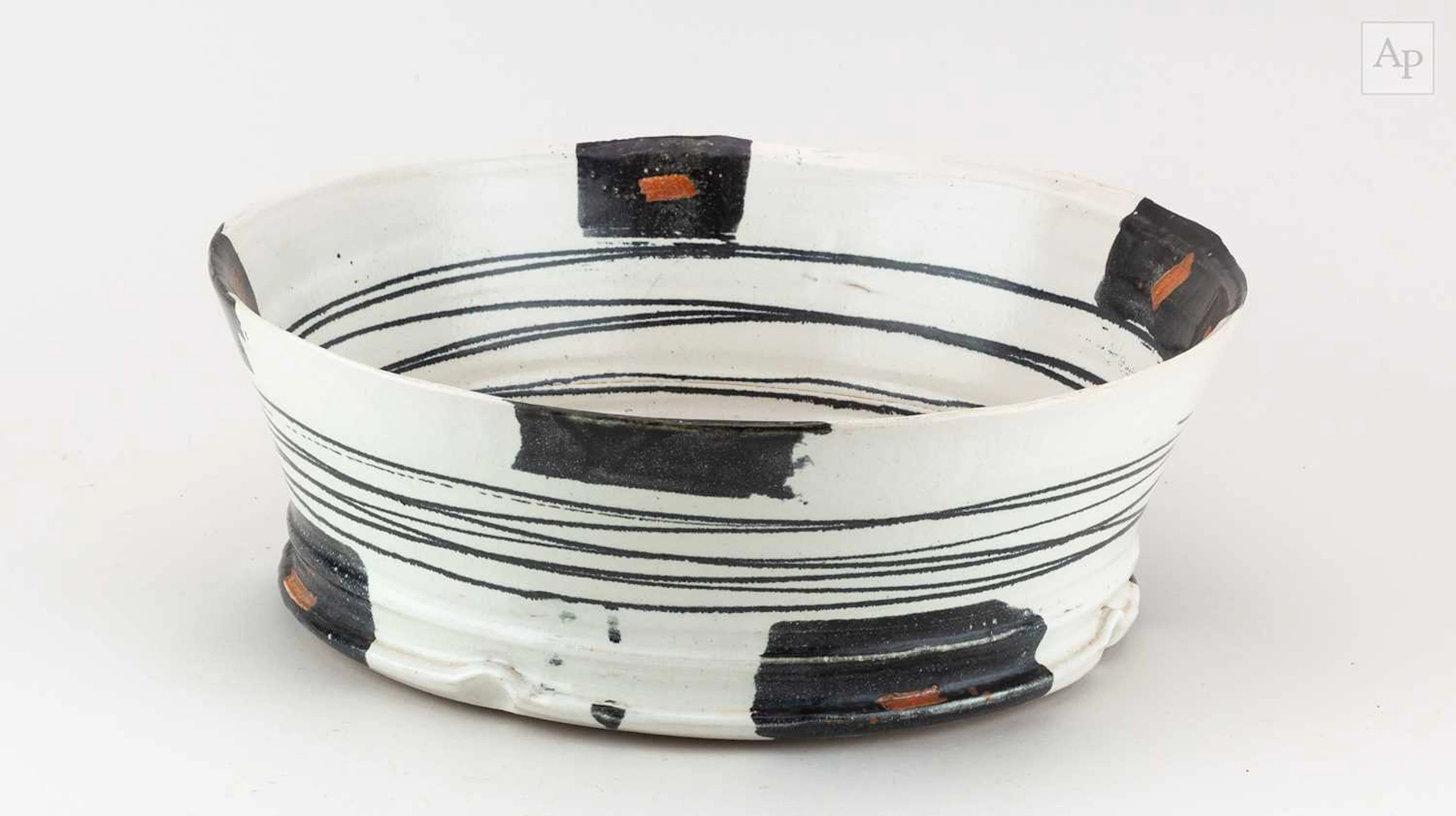 A large stoneware bowl covered in pale grey glaze with iron decoration