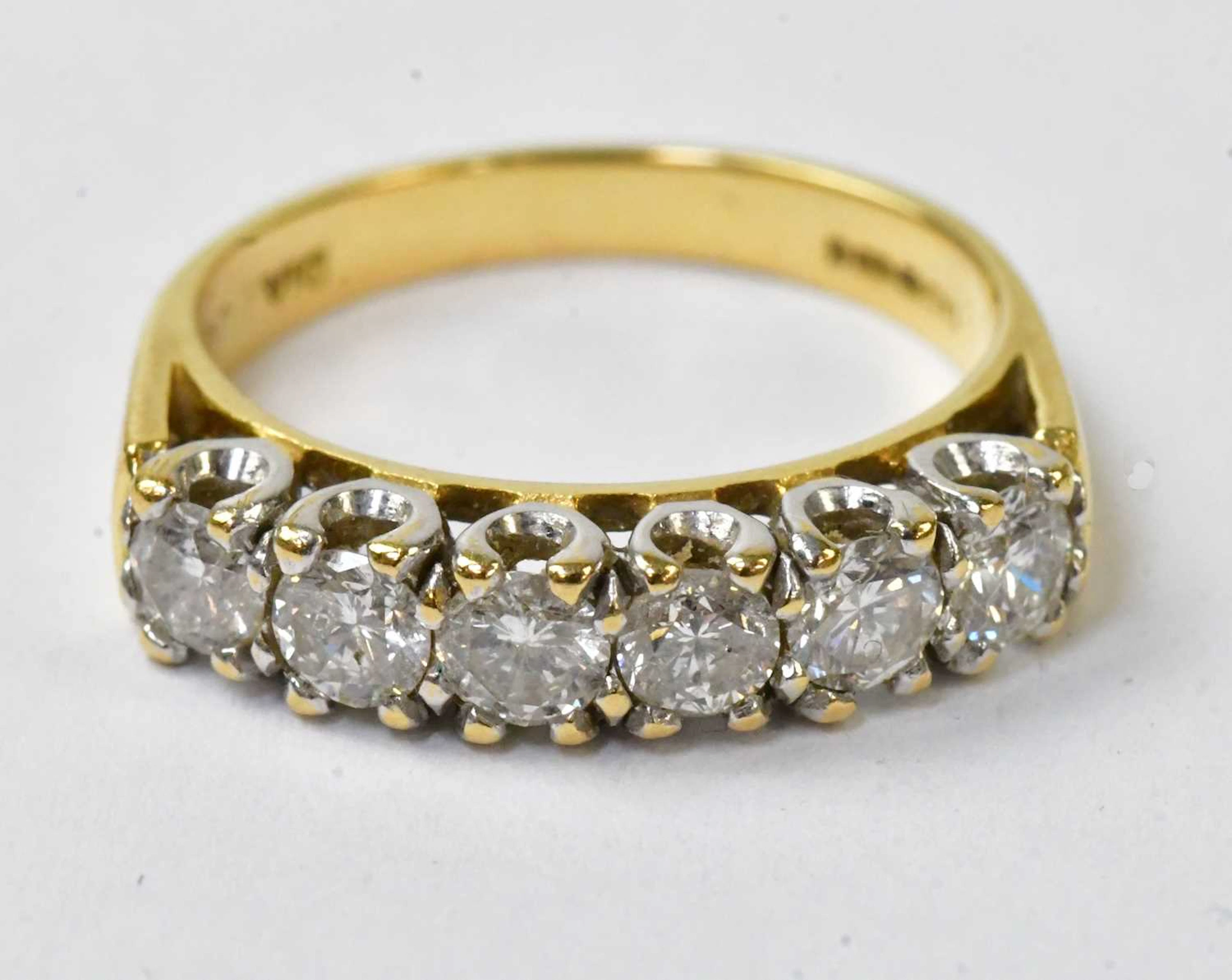 An 18ct yellow gold ring set with a row of six diamonds in white metal setting