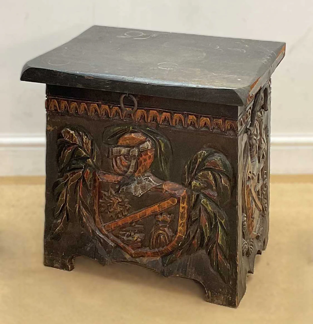 A stained wooden coal box with carved coat of arms to the front