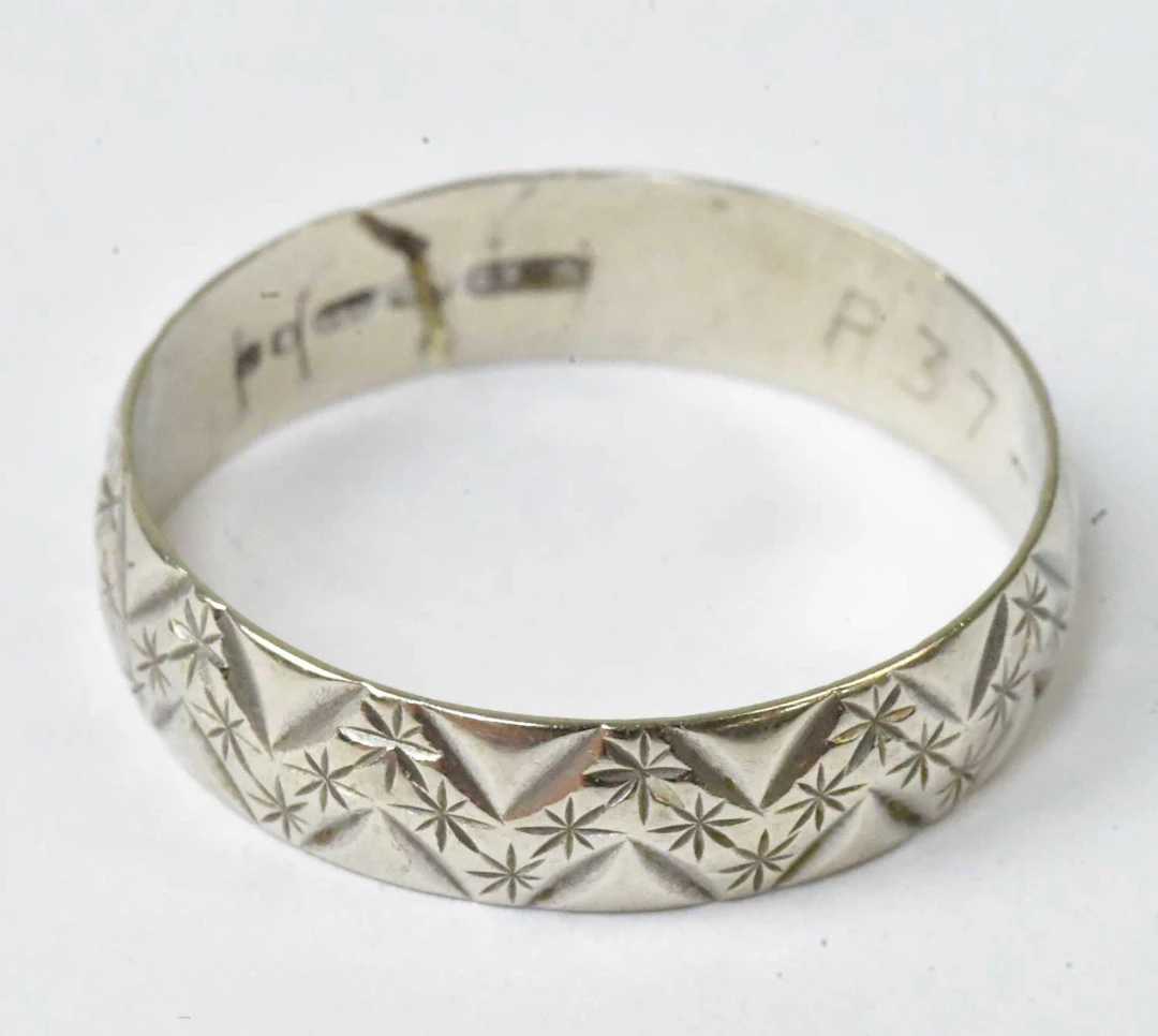 A 9ct white gold wedding band with engraved decoration