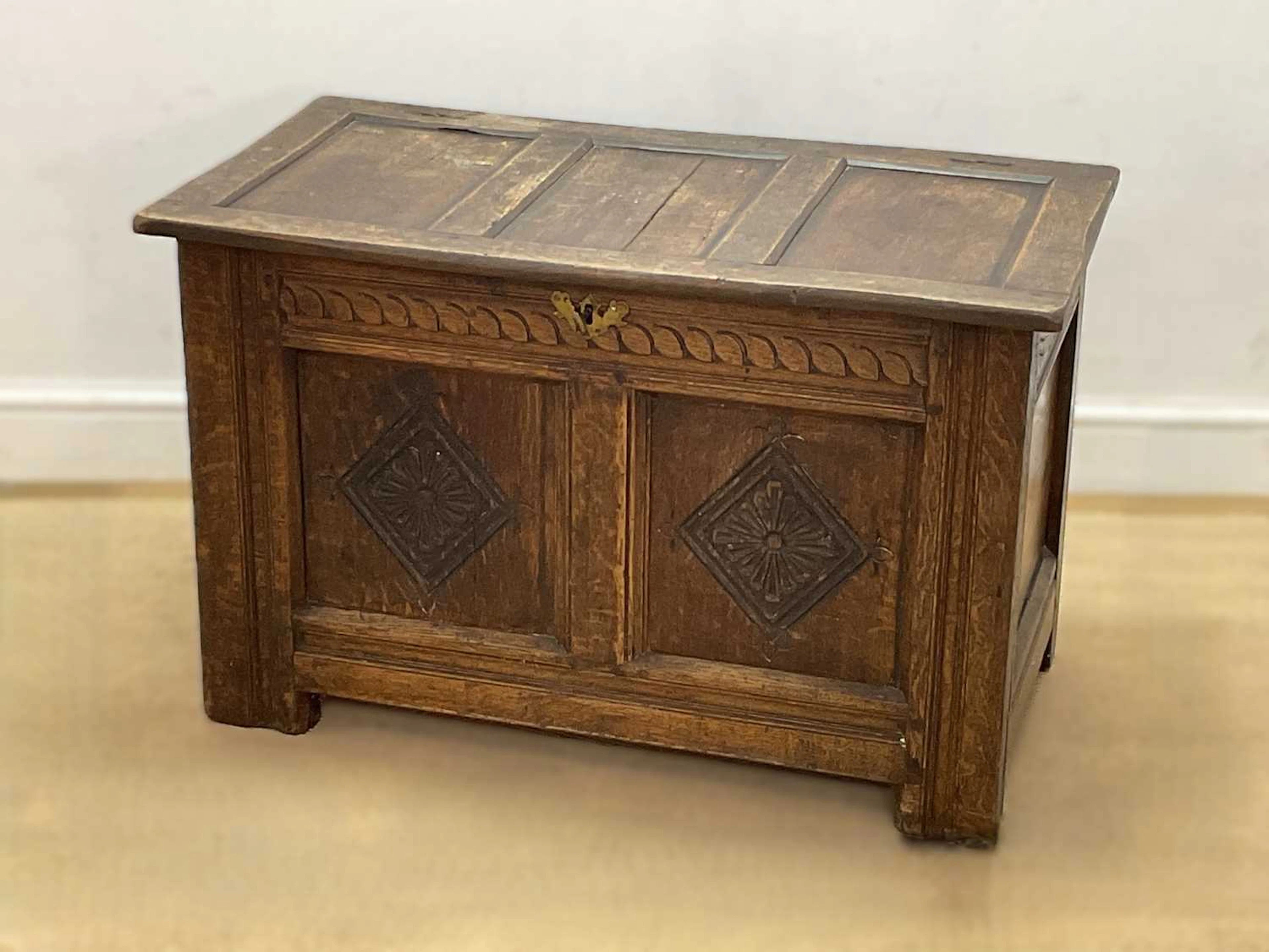 A carved oak coffer with geometric lozenge motifs to the front panels