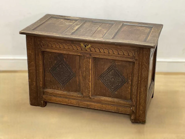 A carved oak coffer with geometric lozenge motifs to the front panels
