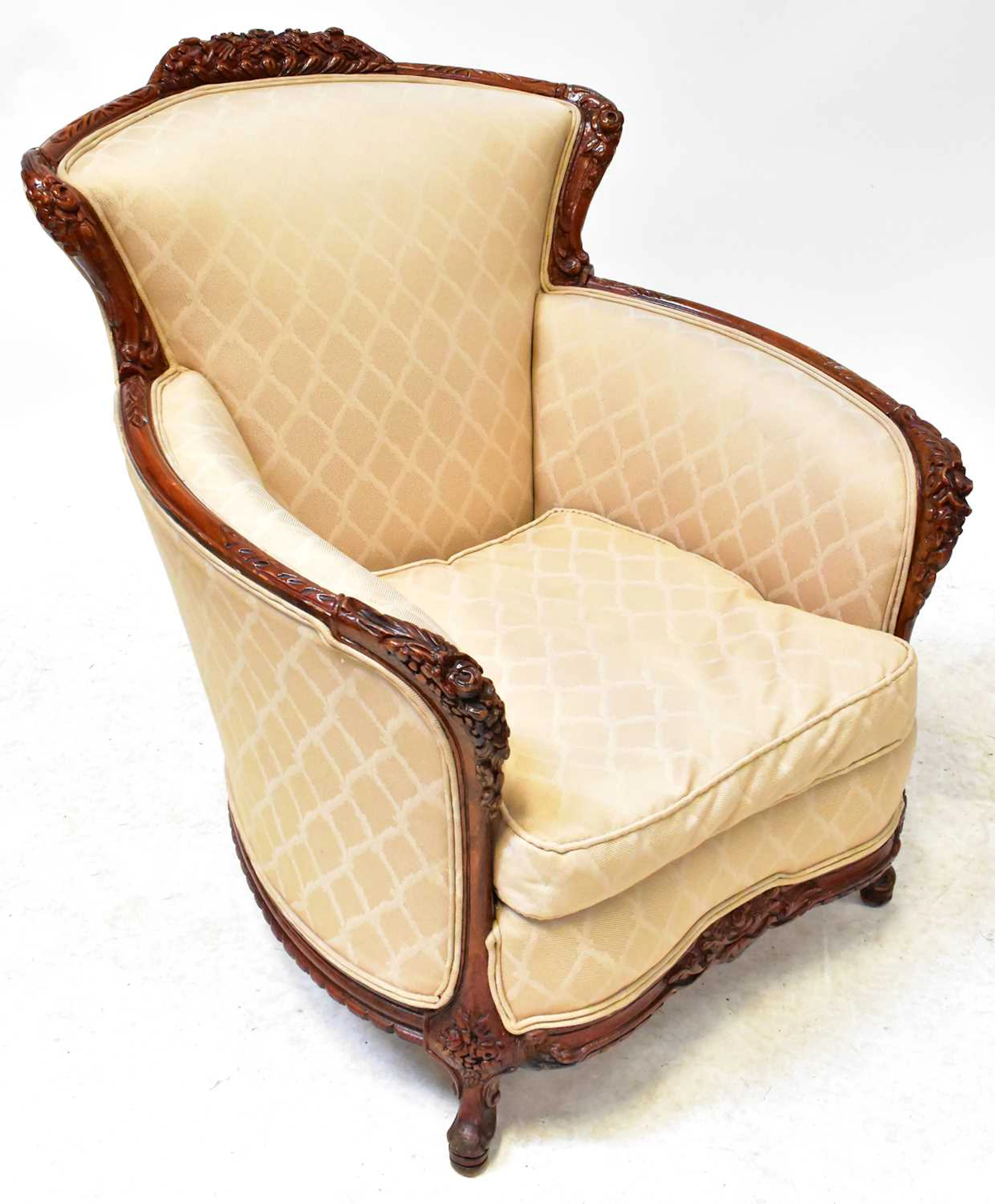 A Victorian-style walnut tub armchair with carved scroll and flowerhead detail
