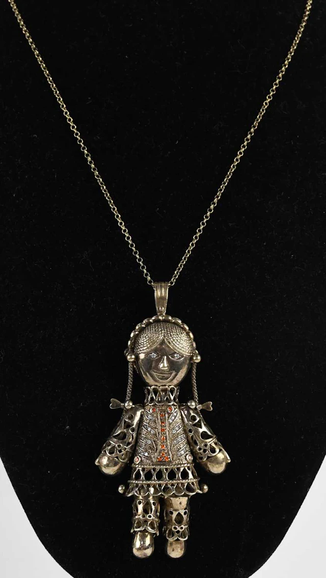 A 925 silver gilt articulated orange and white stone set rag doll pendant