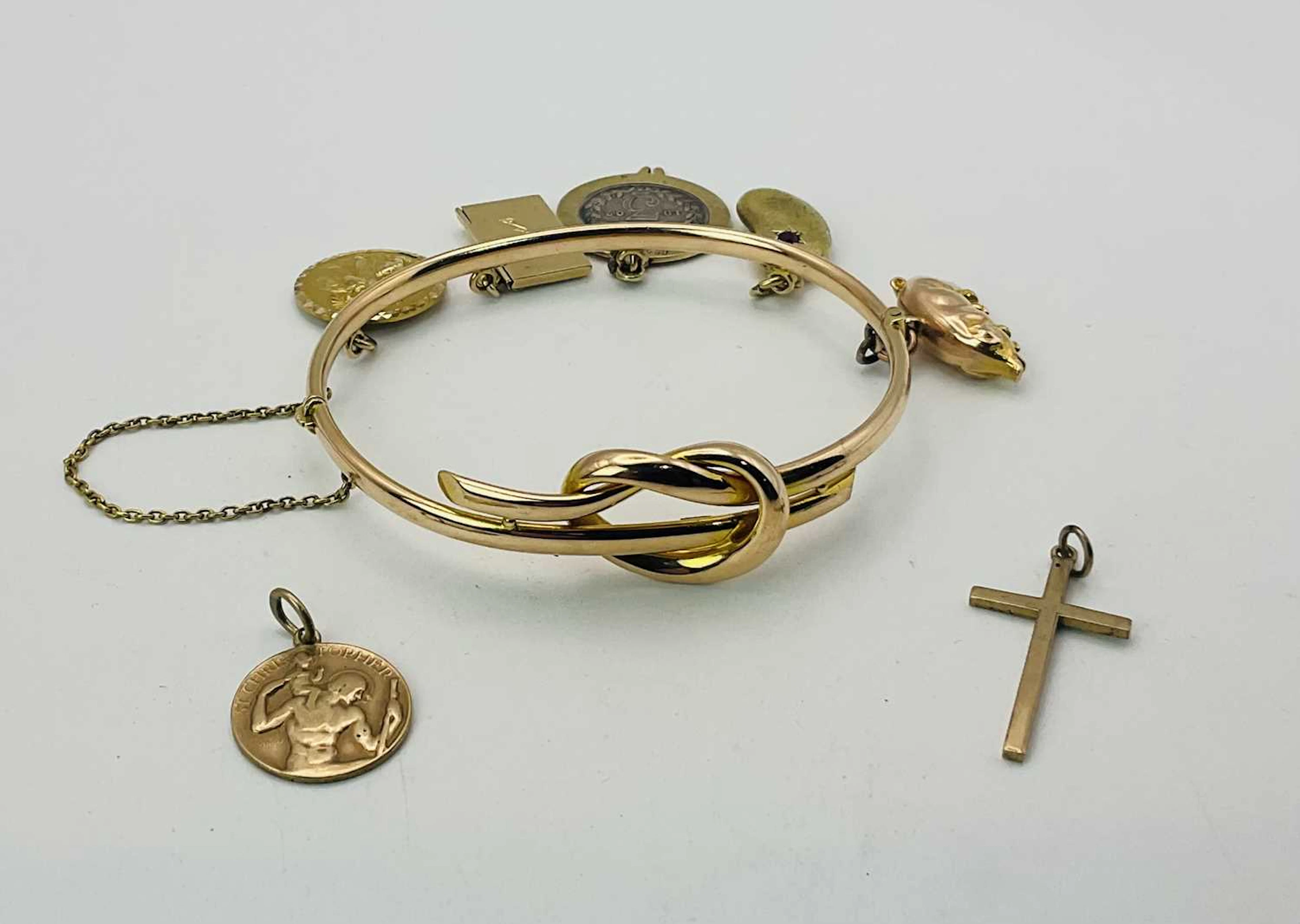A 15ct gold love-knot charm bangle with a 9ct gold St