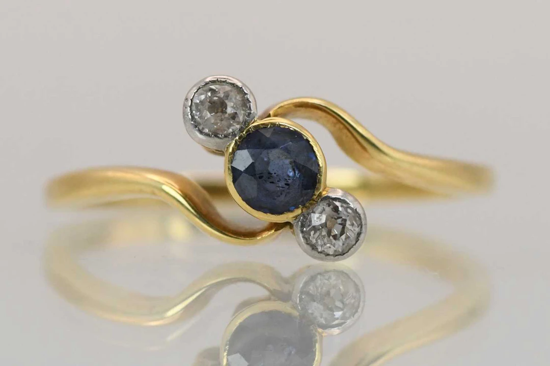 A yellow metal sapphire and diamond three stone crossover ring