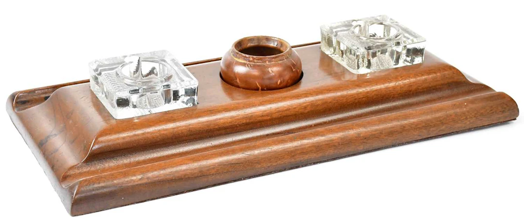 A vintage wooden desk companion with two pressed glass...
