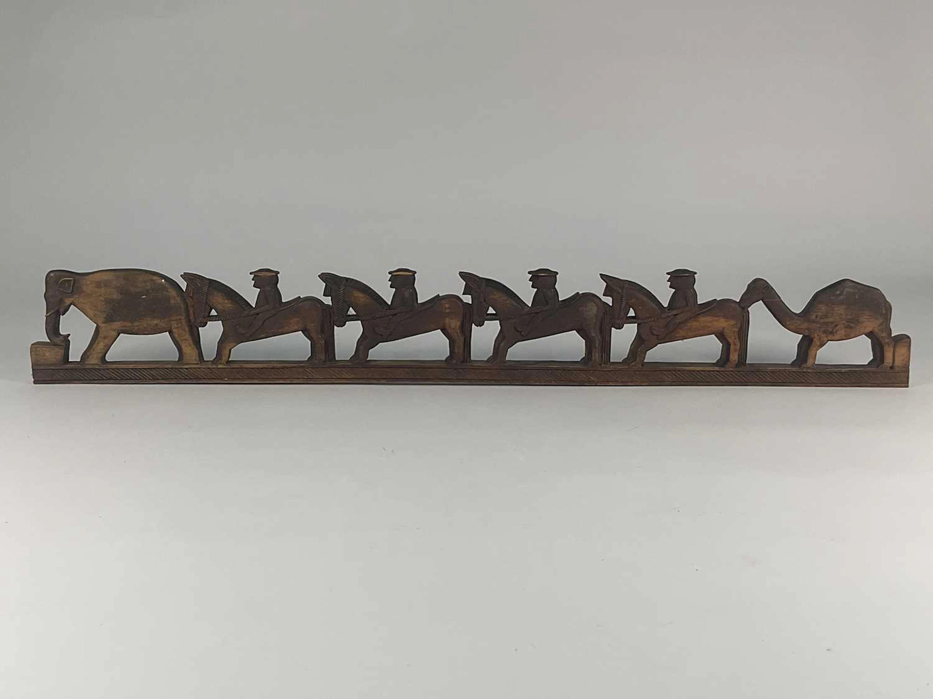 A carved wooden frieze depicting figures riding horses...