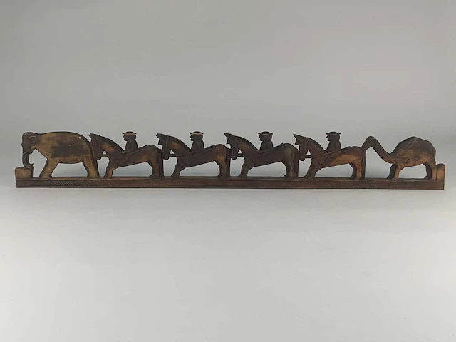 A carved wooden frieze depicting figures riding horses...