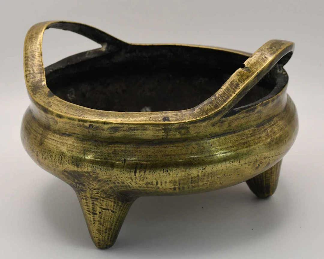 A 19th century Chinese polished bronze circular twin handled censer
