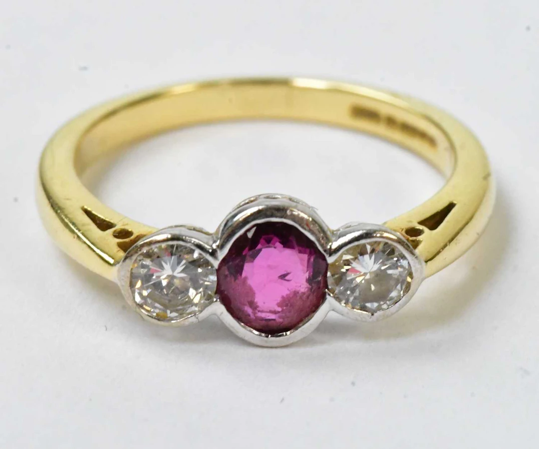 An 18ct yellow gold ring set with a central ruby flanked...
